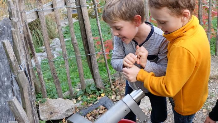 Wasserspirale Zwei Jungs drehen an einer Kurbel, um aus einem Rohr Wasser zu befördern