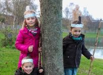 Drei Kinder, verkleidet als Indianer, stehen um einen Baum herum