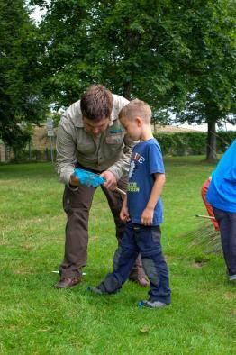 ein Ranger begutachtet mit einem Jungen dessen Fang in einem Käscher