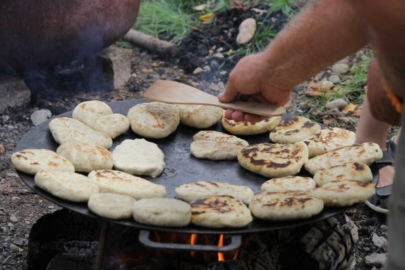 selbstgemachte Brötchen backen auf einer gußeisernen Pfanne über einem Lagerfeuer aus