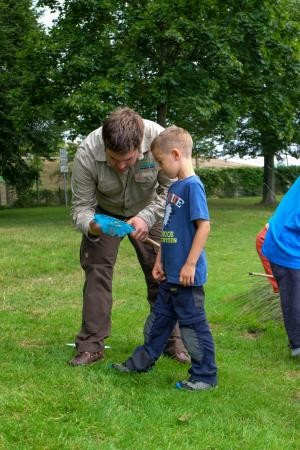 Ranger betrachtet zusammen mit einem Jungen den Inhalt eines Käschers