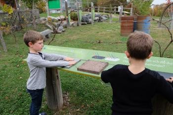 Zwei Kinder an Steintafeln im Klimawandelgarten