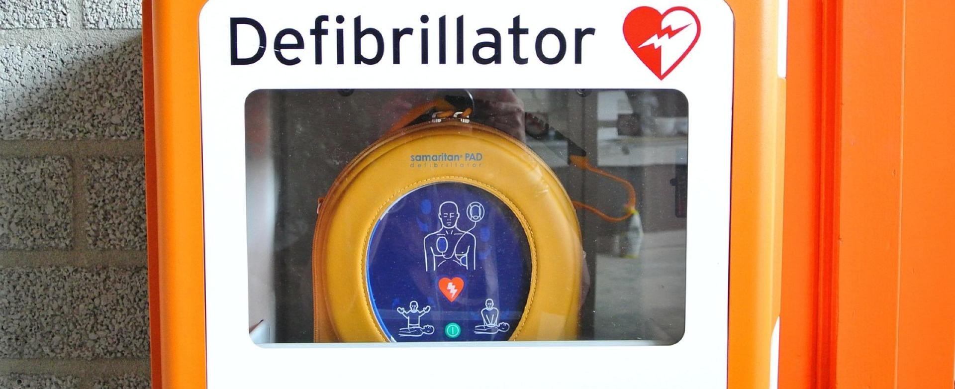 Defibrillator Defibrillator in einem orangenen Rahmen mit Sichtfenster
