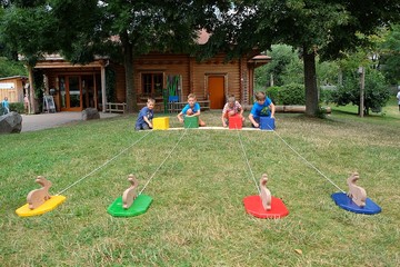 vier Jungs versuchen jeweils, ihre an einer Kurbel befestigten Hasen am schnellsten zu sich zu ziehen